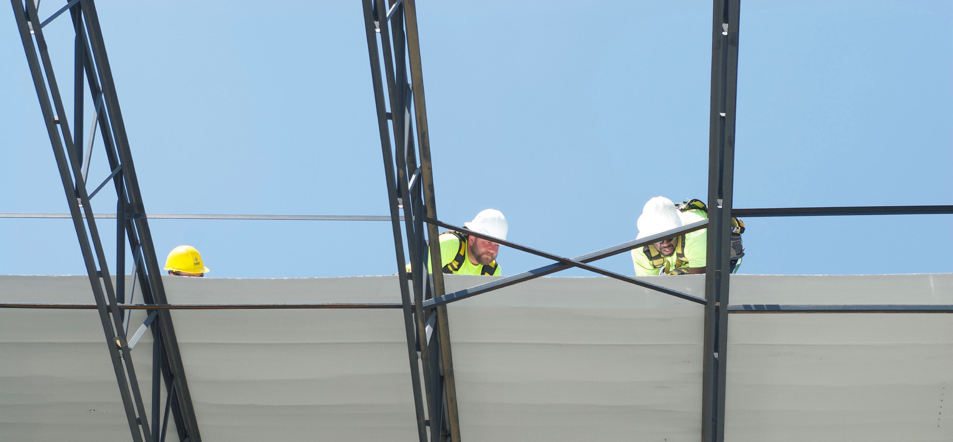 Crew installing barrier on a metal building roof